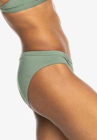 Olive zelené bikiny s hladkým, elastickým materiálom a bezšvíkovými okrajmi a s klasickým strihom pre pokrytie.