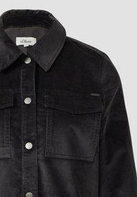 Zwarte corduroy jas met kraag, twee borstzakken en drukknoopsluiting. Getextureerde stof met verticale ribbels.