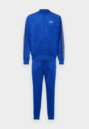 Blue EA7 Emporio Armani two-piece tracksuit with zip-up jacket and elastic-cuffed pants, featuring side stripes and logo on chest and thigh.