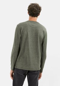 Grøn langærmet t-shirt med tekstureret overflade, rund halsudskæring og lige skæring. Har minimal syning og ingen synlige logoer.
