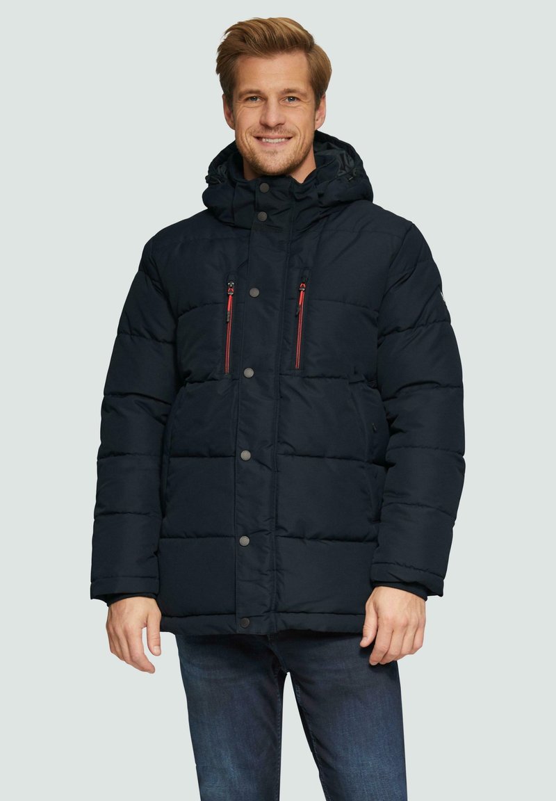 Marineblauwe gewatteerde jas met capuchon, voorzien van rode ritszakken en drukknoopsluitingen. Gelaagd, geïsoleerd ontwerp tot de knie.
