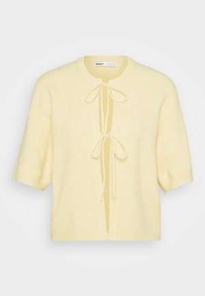 Cardigan s kratkimi rokavi iz mehke, svetlo rumene tkanine. Ima okrogel izrez, odprt sprednji del z zavezovanjem in rebraste obrobe na spodnjem robu.