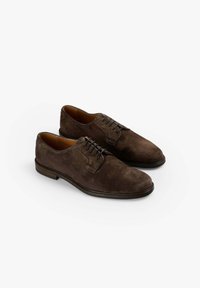 Zapatos de ante marrón con cordones, presentan una puntera redondeada, forro de cuero suave y un diseño minimalista con acentos de suela negra.