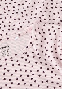 Jasnoróżowy top z prążkowanej tkaniny z ciemnofioletowymi groszkami i zaokrąglonym dekoltem, z metką zawierającą informacje o rozmiarze.