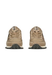 Para beżowych zamszowych sneakersów z brązowymi akcentami, grubymi białymi podeszwami środkowymi i czarnymi podeszwami z falistym wzorem, widoczna z przodu.