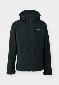 Veste softshell Columbia noire avec capuche, fermeture éclair intégrale à l'avant, poche zippée sur la poitrine et bandes ajustables aux poignets.