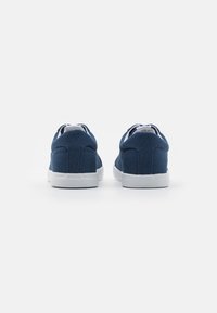 Sneakers in tela navy con suole in gomma bianca, punta arrotondata e lacci piatti, caratterizzate da una tomaia strutturata e dettagli di cucitura minimal.