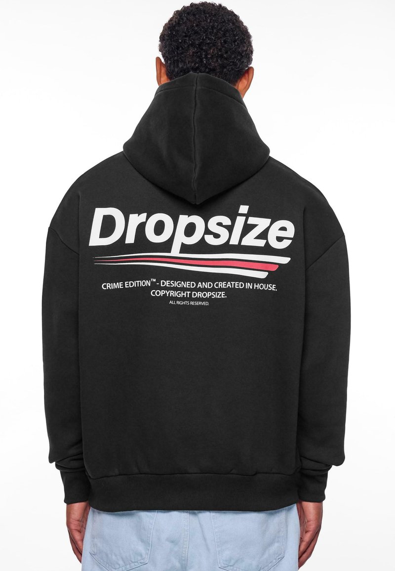 Hoodie noir avec une capuche à cordon de serrage. "Dropsize" imprimé en grandes lettres blanches au dos, avec des accents rouges et noirs. Texture douce.