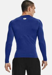 Langærmet atletisk skjorte i livlig blå, lavet af strækstof med en tætsiddende design og flade sømme, der har et lille logo på ryggen.