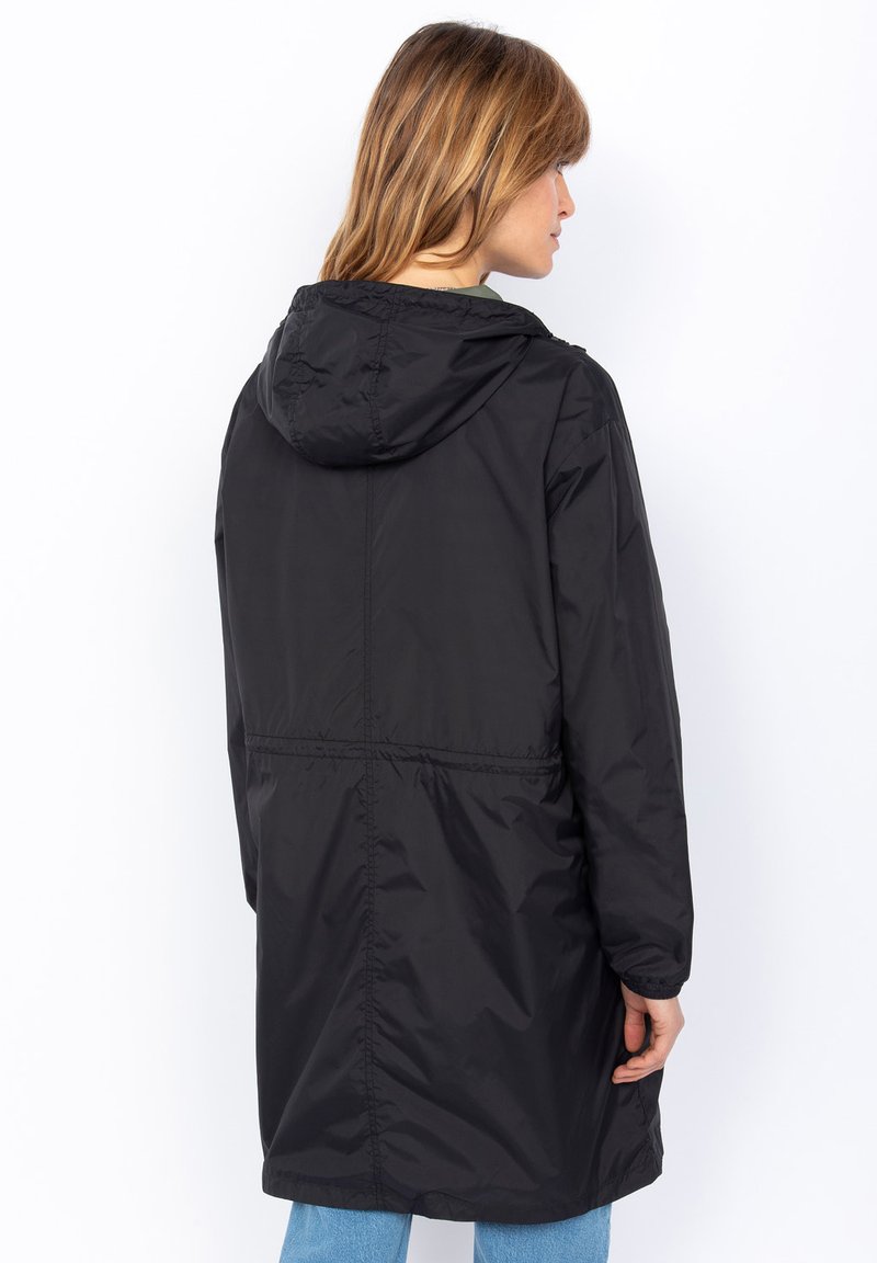 Veste noire imperméable avec capuche, dotée d'une taille cintrée, de manches longues et d'une texture lisse et brillante. A aucun motif ou accent visible.