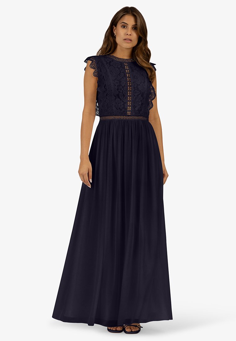 Robe maxi bleu marine avec des détails en dentelle, des manches à bords scallopés et un corsage ajusté. Jupe fluide avec une ceinture texturée et des accents transparents.