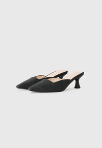 Black suede pointed-toe mules with low curved heels and open back, displayed on a plain white background.