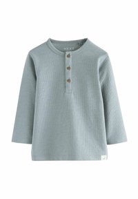 Haut à manches longues bleu clair en tissu texturé, avec un col rond et trois boutons en bois à l'avant. Petite étiquette logo à l'ourlet.