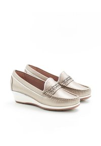 Mocassini a zeppa beige metallico con accenti perforati, texture in pelle liscia, punta rotonda e suola bianca a contrasto.