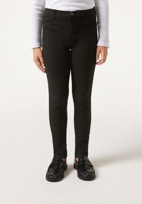 Jeans skinny negros con cintura alta, confeccionados en denim, que presentan un diseño clásico de cinco bolsillos y un cierre de botón. Textura suave.