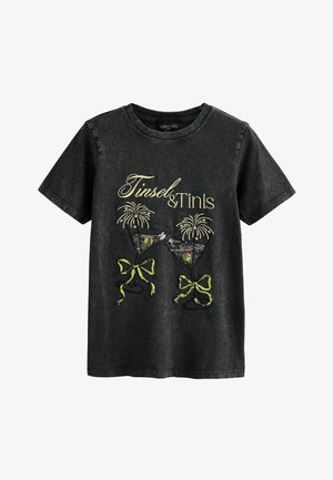 Mustast puuvillast ümara kaelusega T-särk, millel on kuldsete ja roheliste tikanditega tekst "Tinsel & Tinís" ning kokteiliklaaside kujundus vibuidega.