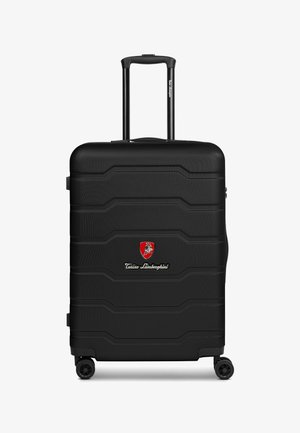 Schwarzer Hartschalenkoffer mit strukturiertem Oberflächen, horizontalen Rillen, teleskopischem Griff und vier Rädern. Mit einem Lamborghini-Logo.