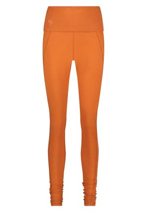 Oranje legging met een brede tailleband. Gladde, rekbare stof. Gehaakte details bij de enkel. Subtiel logo op de tailleband.