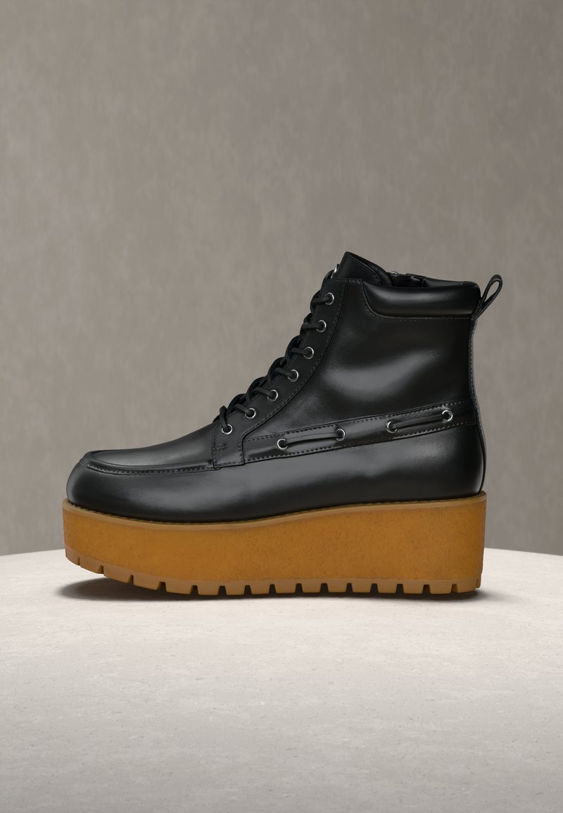 Czarny skórzany botek za kostkę z okrągłym noskiem, sznurowaniem z przodu oraz gumową podeszwą na platformie; posiada kontrastującą gumową podeszwę w kolorze naturalnej gumy i metaliczne przelotki.