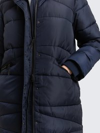 Tmavě modrý prošívaný kabát s zapínáním na zip, žebrovanými manžetami a šikmým prošíváním. Obsahuje boční kapsy a má hladký lesklý povrch.