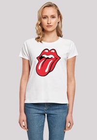 White cotton t-shirt featuring a large red tongue logo in the center. The design includes black outlines and white teeth details.