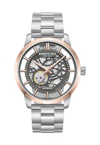 Silverfärgad rostfri klocka med en grå skelettskiva, rosaguld accenter och klara timmarkörer och visare. Automatisk rörelse synlig genom skivan.