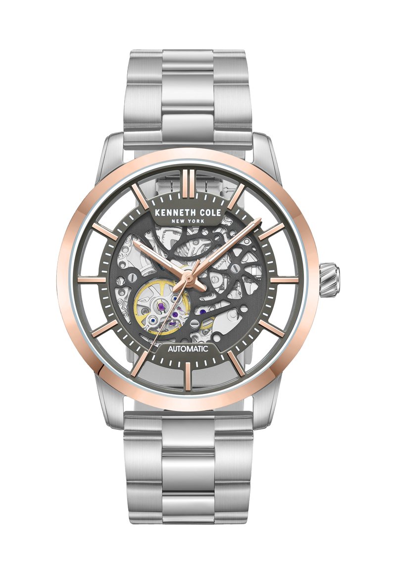 Silverfärgad rostfri klocka med en grå skelettskiva, rosaguld accenter och klara timmarkörer och visare. Automatisk rörelse synlig genom skivan.