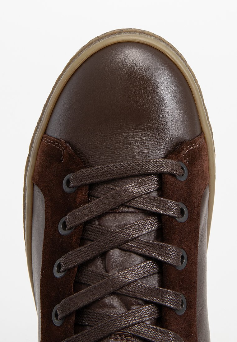 Braune Leder- und Wildledersneaker mit runder Zehenpartie, strukturiertem Obermaterial, braunen Schnürsenkeln und Gummisohle, die ein geschichtetes Design und kunstvolle Nähte aufweisen.