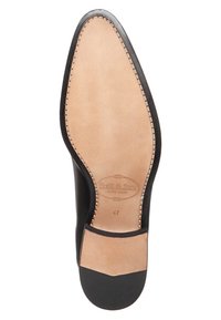Semelle de chaussure en cuir noir avec doublure en cuir beige. Détail de bord cousu, bout arrondi, logo embossé et taille 41 marquée à l'intérieur.