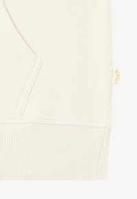 Cream-colored sweatshirt fabric with a soft texture. Features a side pocket, ribbed hem, and a small, beige logo tag on the seam.