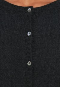 Σκοτεινό γκρι κάρντιγκαν από μαλακό, υφασμάτινο πλέγμα με στρογγυλή λαιμόκοψη και πέντε κυκλικά κουμπιά μπροστά.