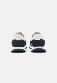 Marineblaue und weiße Sportschuhe mit Obermaterial aus Wildleder und Synthetik, gepolstertem Kragen, dämpfender Zwischensohle, strukturiertem Gummilaufsohle und minimalistischem Design.