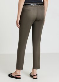 Khaki trousers with a slim fit, flat front, and two back pockets. Paired with black strappy sandals, showcasing a smooth texture.