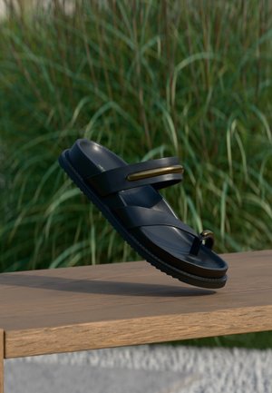 Zwarte sandaal met een ontwerp van dubbele bandjes en een ronde teenlus. Gemaakt van zacht materiaal met een gestructureerde zool en een gouden sierelement.