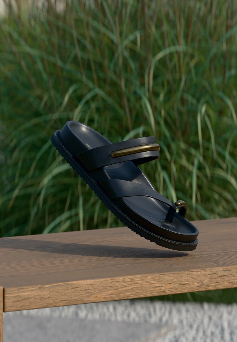 Μαύρο σανδάλι με διπλή σχεδίαση λουριών και στρογγυλό δαχτυλοδέτη. Κατασκευασμένο από απαλό υλικό με υφασμένη σόλα και χρυσές διακοσμητικές λεπτομέρειες.