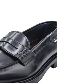 Black leather loafer with a smooth finish, featuring a stitched mock strap and a sturdy sole. Interior lined with dark fabric.