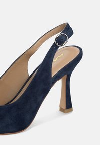 Chaussure slingback en daim bleu marine avec un orteil arrondi, un talon pointu et un accent en boucle en métal. Doublure intérieure lisse et détails de couture subtils.
