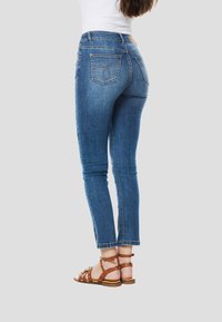 Blauwe denim jeans met een aansluitend model, lichte rekbaarheid en rafelige zoom. Voorzien van achterzakken met gedetailleerde stiksels en een tailleband met middenhoogte.