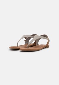 Gray sandal with a textured strap and a thin heel. Features a metal buckle and a flat, brown sole. Simple and minimalistic design.