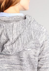 Felpa grigia con motivo e finitura texturizzata, dotata di cappuccio con cordino e rivestimento interno di colore azzurro.