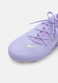 Light purple football shoe with textured surface, contrasting yellow Nike logo, and intricate lace design. Features molded studs on the sole.