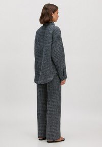 Gewebtes Outfit mit Karomuster in Marineblau und Weiß, bestehend aus einem übergroßen Hemd und weit geschnittenen Hosen. Der Stoff hat ein strukturiertes, weiches Erscheinungsbild.