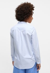 Helles blau-weiß gestreiftes Langarmhemd mit Rückenpasse, abgerundetem Saum und geknöpften Manschetten. Baumwollstoff mit glatter Textur.