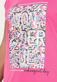 Růžové tričko s krátkým rukávem, zdobené barevným květinovým potiskem, s nápisem "WONDERFUL" ve stříbrných písmenech a akcenty z kamínků na jedné straně.