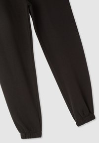 Pantaloni sportivi neri con texture liscia, gambe affusolate e polsini elastici alle caviglie. Design semplice e funzionale, adatto per un look casual.