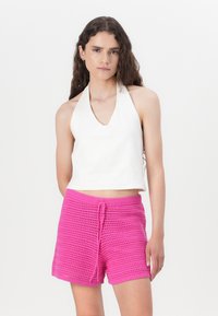 White halter crop top with a deep neckline paired with pink knitted shorts featuring a textured pattern and drawstring waist.