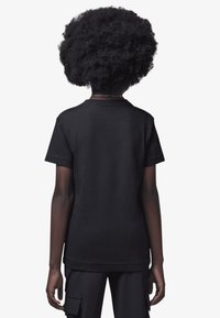 Mustast puuvillast T-särk ümar kaelusega, lühikeste varrukatega ja sirge äärega. Kangas tundub sile, ilma nähtavate mustrite või aksentideta.