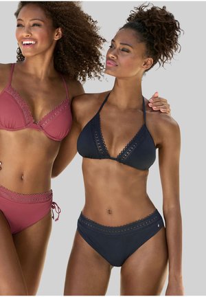 Zwei Frauen in Bikinis. Eine trägt einen burgunderfarbenen Bikini mit gewelltem Saum; die andere trägt einen marineblauen Bikini mit ähnlichen Details.