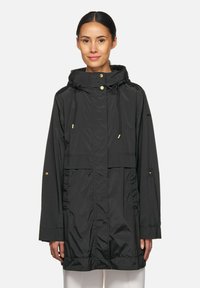 Waterafstotende zwarte jas met een trekkoordcapuchon, elastische manchetten, voorzakken en accenten van goudkleurige hardware. Gladde, lichte stof.