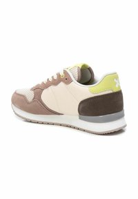 Zapatilla que presenta una mezcla de ante beige y marrón, paneles de malla, suela gris y detalles en verde lima en el talón y los ojetes.